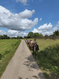 Groupe de cavaliers en balade à cheval sur une petite route de campagne dans le Morbihan en été